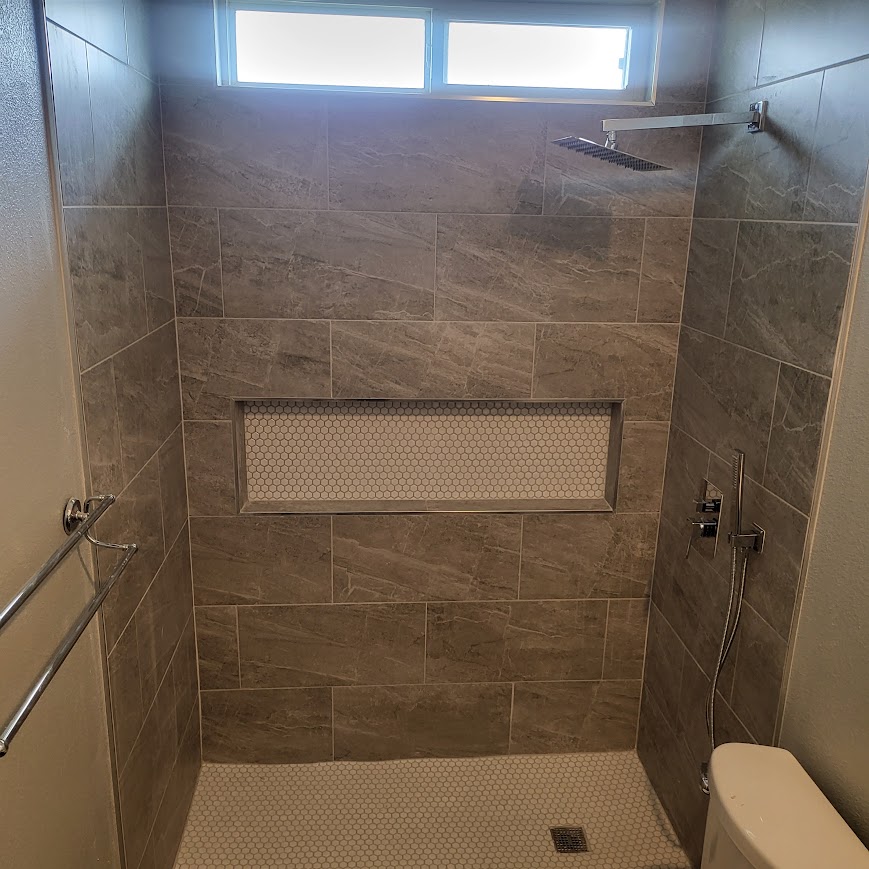 Walk-in tile shower with mosaic niche and rain shower head
