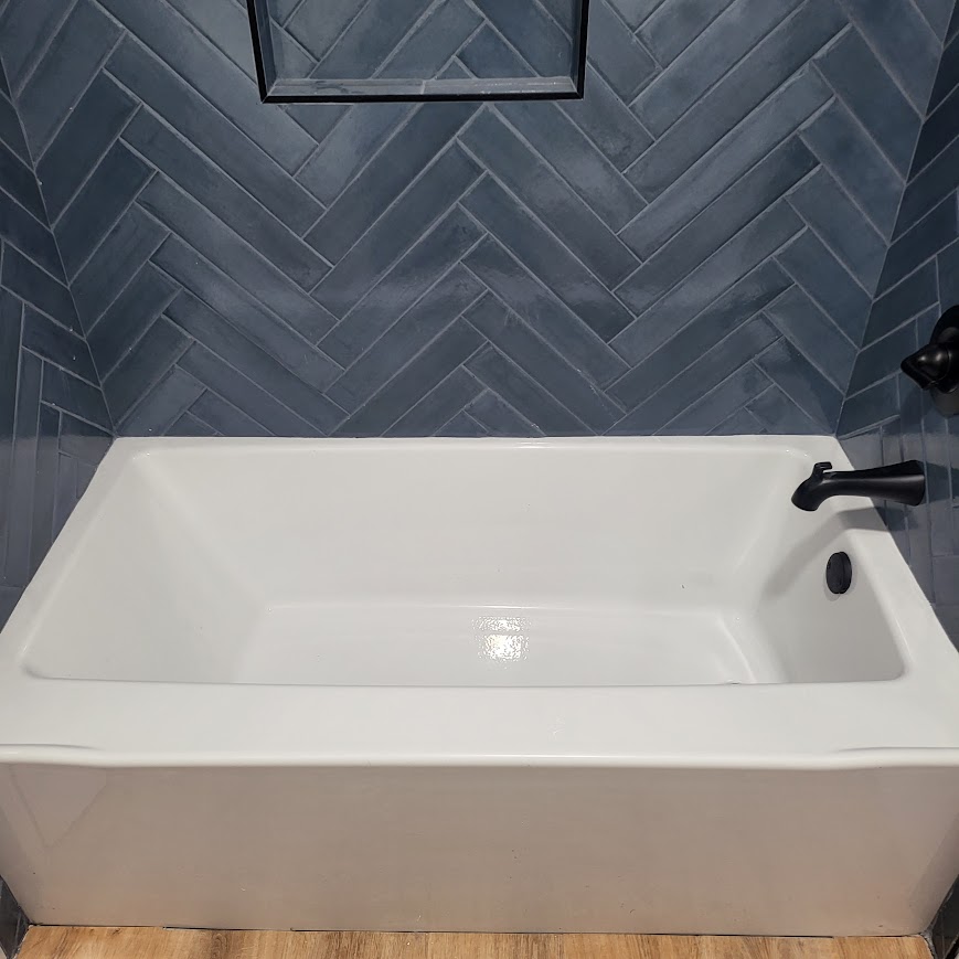 Freestanding tub with blue herringbone tile surround, remodeled bathroom
