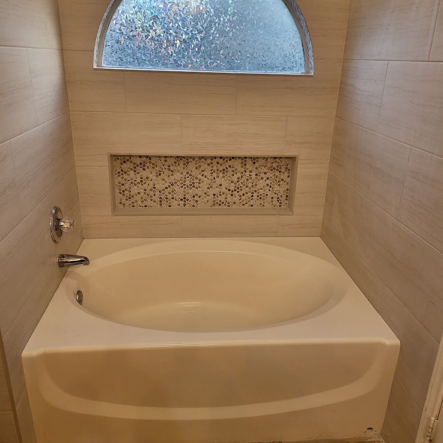 Soaking tub with pebble tile niche and arched window, bathroom remodel
