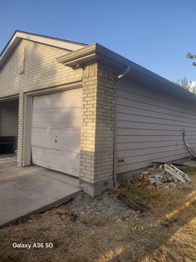 Rebuilt garage corner with new brick masonry after repair, San Marcos, TX