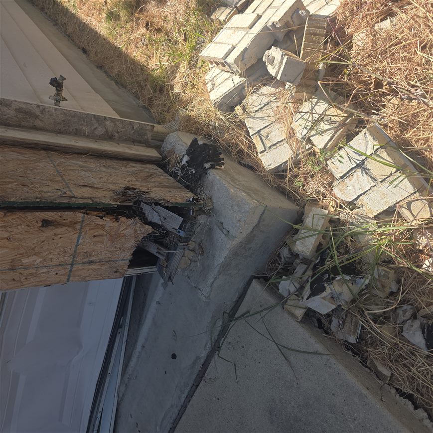 Collapsed brick masonry and rotted OSB sheathing at a garage corner before repair, San Marcos, TX