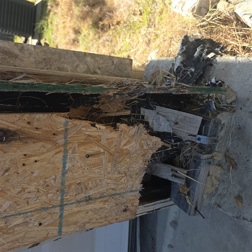 Close-up of rotted sheathing and displaced brick at a garage corner before repair