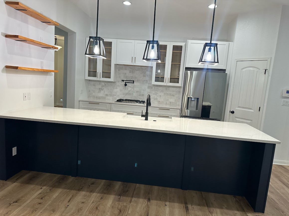 Georgetown, TX kitchen after remodel — navy island, white quartz counters, black lantern pendants