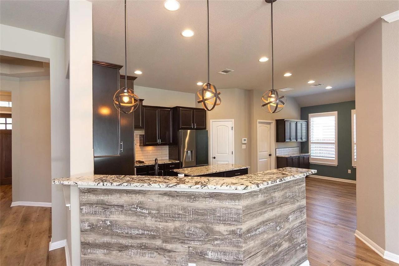 Georgetown, TX kitchen before remodel — dated dark cabinets and busy granite island