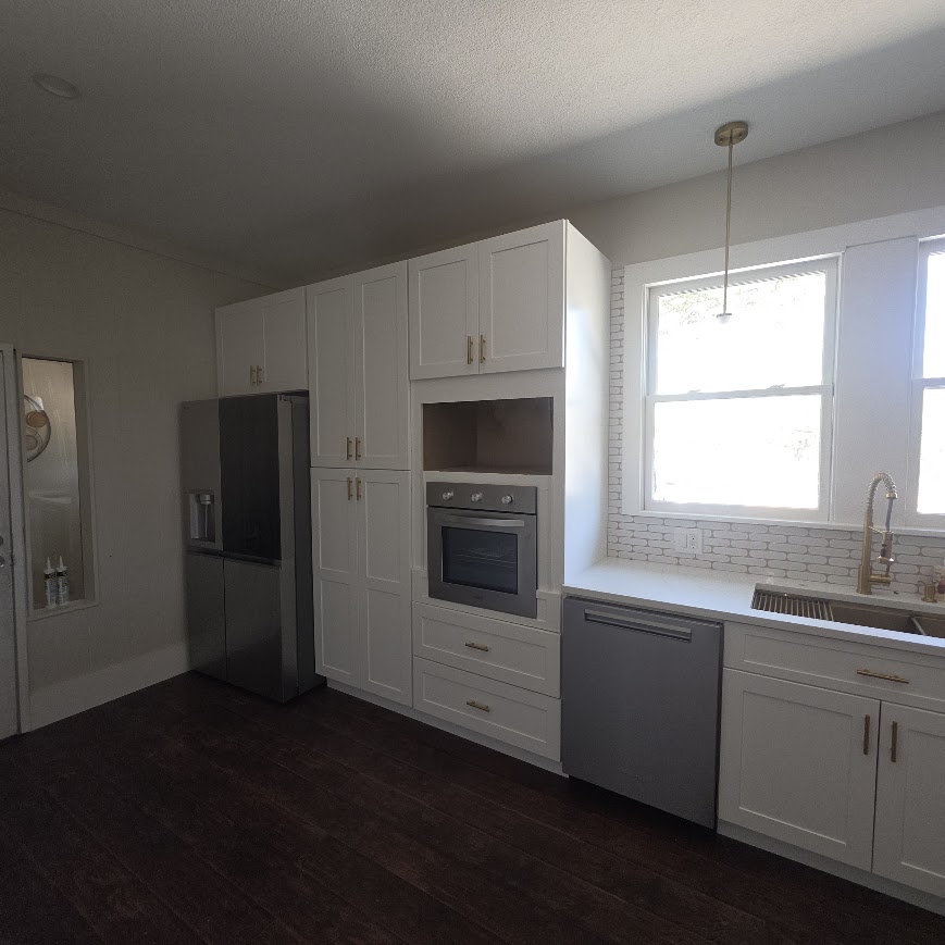 Vintage Central Texas kitchen after remodel — full white cabinetry with built-in appliances