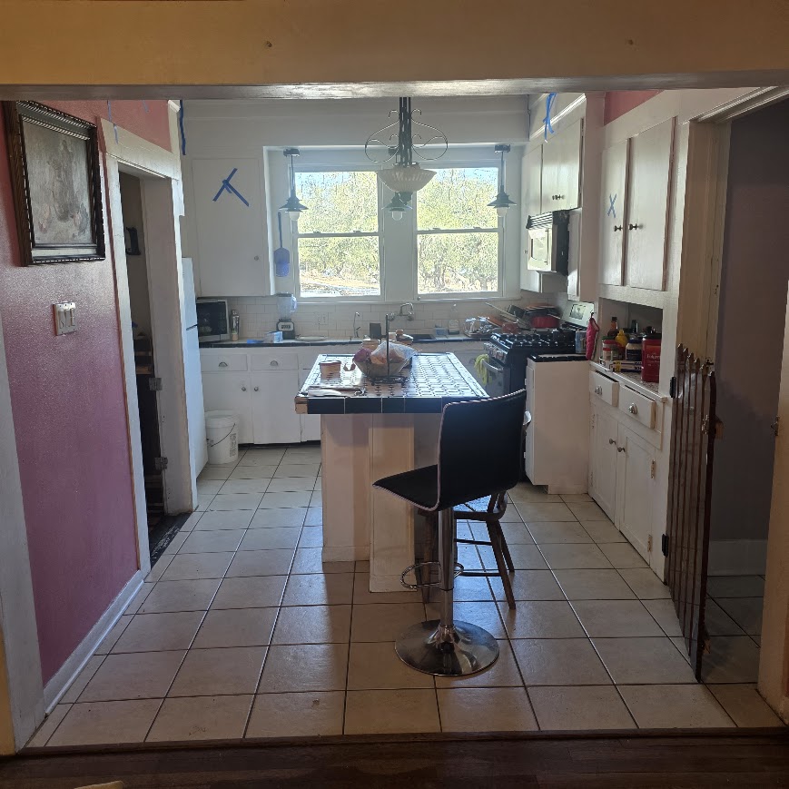 Vintage Central Texas kitchen before remodel — pink walls, terracotta tile floor, makeshift island