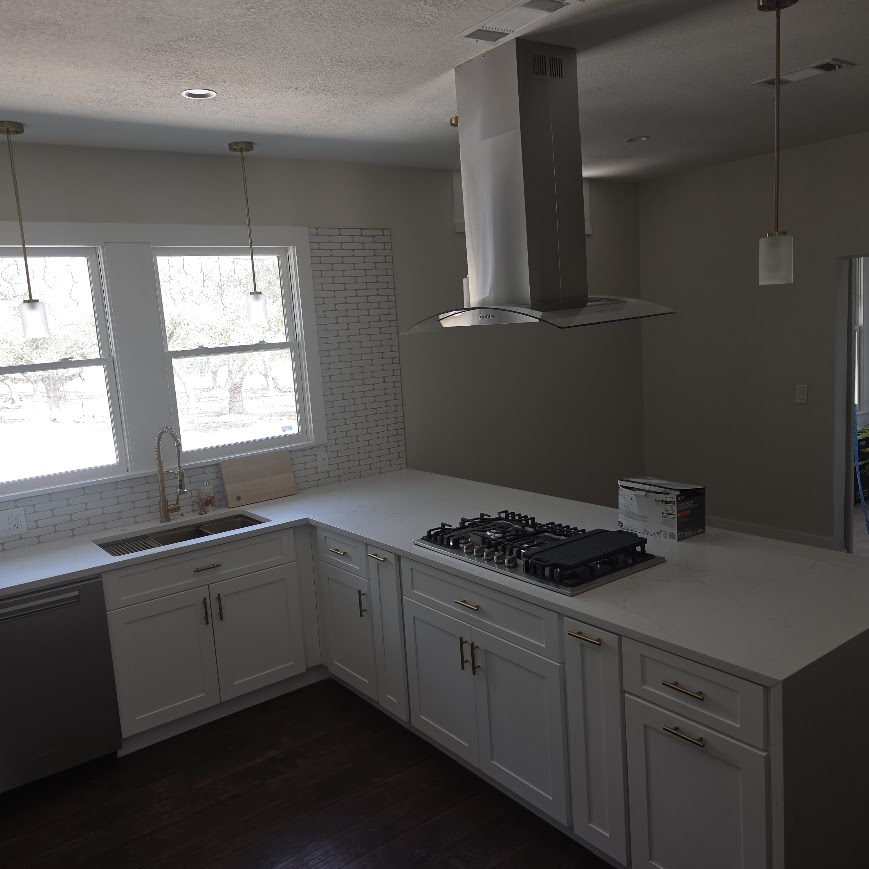 Vintage Central Texas kitchen after remodel — waterfall quartz island with suspended range hood