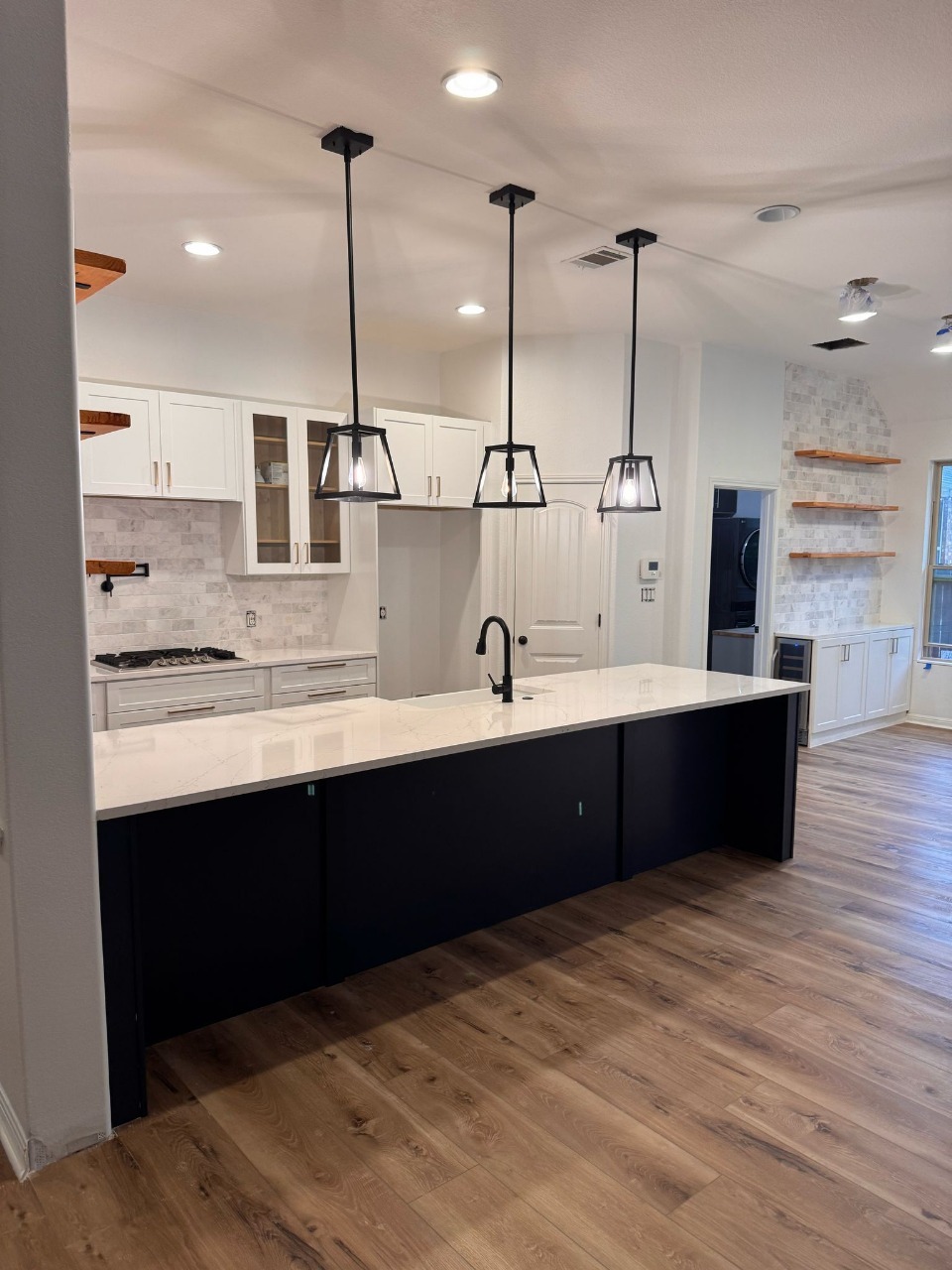 Open-concept kitchen remodel by House Genius in Austin, TX — navy island, quartz counters and LVP flooring